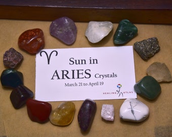 May include: A set of crystals for the zodiac sign Aries. The crystals are arranged in a circle around a card that reads "Sun in Aries Crystals March 21 to April 19". The crystals are various colors, including red, green, purple, and white.