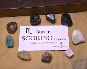 May include: A set of crystals for Scorpio zodiac sign, with a card that says "Sun in Scorpio Crystals, October 23 to November 21". The crystals are brown, black, white, green, clear, pink, and red.