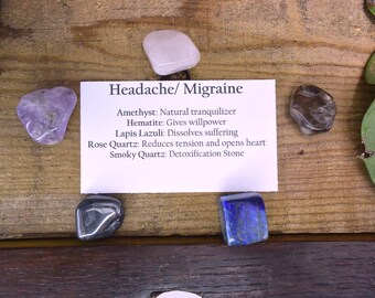 May include: A set of seven crystals for headache and migraine relief. The crystals are amethyst, hematite, lapis lazuli, rose quartz, and smoky quartz. The crystals are arranged on a wooden surface with a card that lists the crystals and their properties.