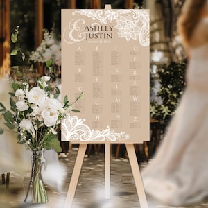 May include: A brown wedding seating chart with white lace detailing. The chart is on an easel and features the names Ashley & Justin and the date August 24, 2014. The chart lists the names of guests by letter.