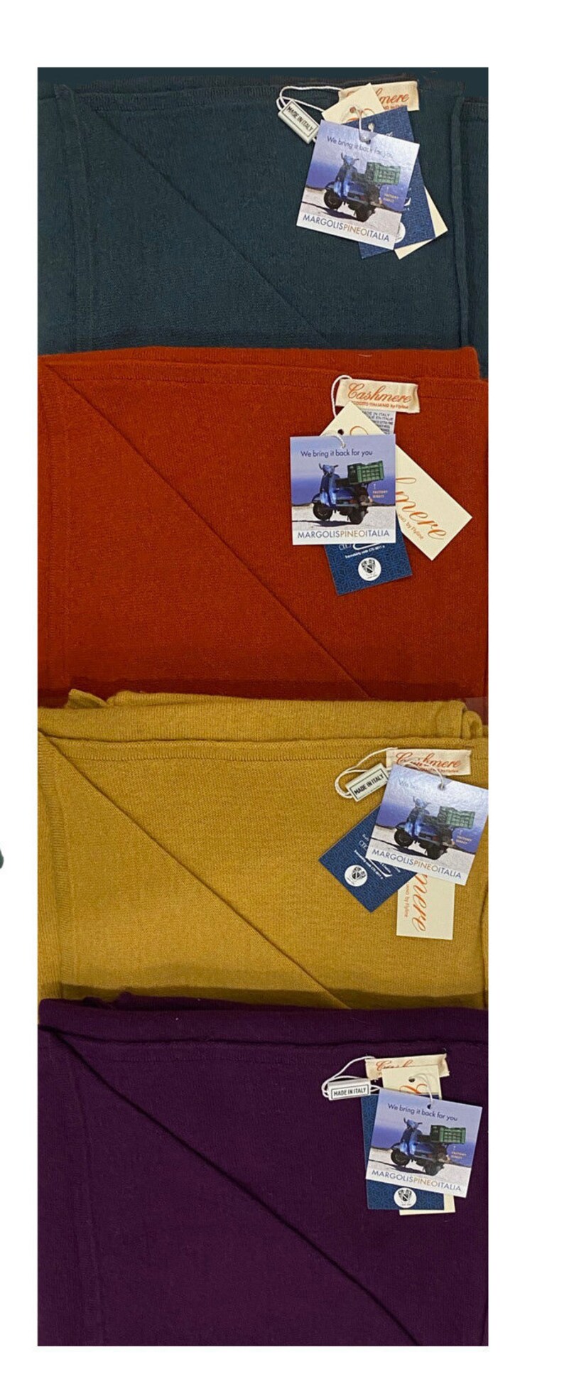 May include: Four folded cashmere scarves in teal, red, mustard yellow, and purple. Each scarf has a tag with a scooter and the text "We bring it back for you" and "MARGOLISPINEOITALIA".