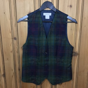 May include: A plaid vest with a dark blue, green, and red pattern. The vest has a label that says "Pendleton" on it.