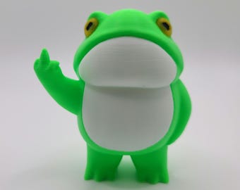 Puede incluir: Figura de rana verde con vientre blanco, mostrando el dedo corazón. La rana tiene ojos amarillos y está de pie. Es un objeto decorativo impreso en 3D.