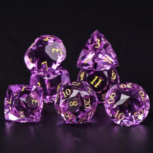 May include: Set of six purple polyhedral dice with gold numbering. The dice are faceted and have various shapes, including a cube, a pyramid, and a sphere. The dice are designed for tabletop role-playing games.