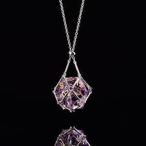 Può includere: Una collana con catena d'argento con un ciondolo a forma di dado in gabbia, sfaccettato e viola. Il dado ha numeri dorati.