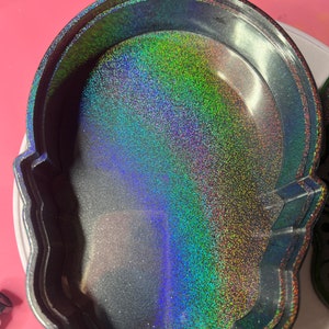 K&ouml;nnte beinhalten: Eine schwarze Sch&auml;del-Schmuckschatulle mit glitzerndem, irisierendem Innenraum. Der Glitter ist eine Mischung aus Gr&uuml;n, Blau und Lila.
