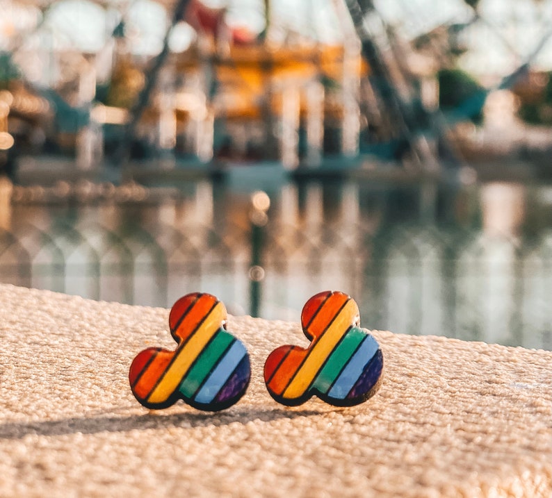 May include: Two rainbow-colored Mickey Mouse-shaped earrings. The earrings are made of a hard plastic material and have a glossy finish.