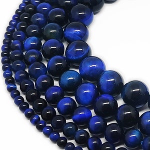 May include: A strand of blue tiger's eye beads, with different sizes of beads, ranging from small to large. The beads are round and have a smooth, polished finish.