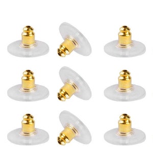 May include: Thirty-six gold-toned earring backs, each with a clear plastic backing. The earring backs are arranged in six rows of six. The earring backs are packaged in a small box with the text "Beadnova Create Your Jewelry" on the top.