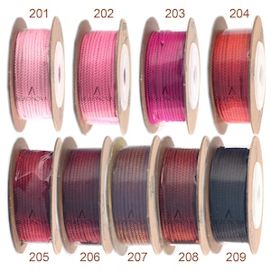 Puede incluir: Nueve carretes de cord&oacute;n, cada uno enrollado en un carrete de cart&oacute;n marr&oacute;n. Los cordones son de varios tonos de rosa, rojo, marr&oacute;n y negro. Los carretes est&aacute;n etiquetados con los n&uacute;meros del 201 al 209.