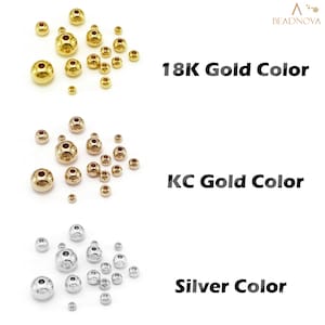 May include: Three groups of round beads in different colors: gold, gold, and silver. The beads are arranged in a scattered pattern on a white background. The text "18K Gold Color", "KC Gold Color", and "Silver Color" is displayed below each group of beads.