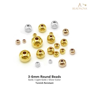 May include: A collection of round beads in gold, light gold, and silver colors, featuring varying sizes from 3-6mm. The beads have a smooth, reflective surface and a central hole for stringing. Text reads: 3-6mm Round Beads, Gold / Light Gold / Silver Color, Tarnish Resistant.