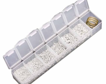 May include: A clear plastic storage box with seven compartments filled with silver jump rings. The box is open and the compartments are filled with different sizes of jump rings. There is a gold jump ring in the last compartment.