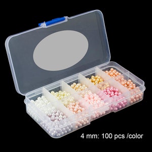 May include: A clear plastic organizer box filled with various colors of 4 mm faux pearls. The pearls are in shades of white, cream, peach, pink, and gold. The text "4 mm: 100 pcs /color" is visible.