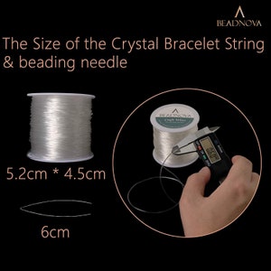 May include: A spool of clear elastic string for jewelry making, measuring 5.2 cm by 4.5 cm. The string is being measured with a digital caliper, showing a measurement of 0.90 cm.