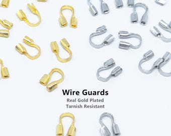 Puede incluir: Una colección de protectores de alambre en forma de U en tonos dorados y plateados, dispuestos sobre un fondo blanco. El texto Wire Guards, Real Gold Plated, Tarnish Resistant y BEADNOVA está impreso en el centro. Estos fornituras son para joyería.
