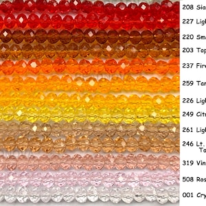 May include: A collection of faceted crystal beads in various colors, including red, orange, yellow, and pink. The beads are strung together, with each strand displaying a different hue. The image also includes text labels for each color, such as "Siam" and "Crystal."