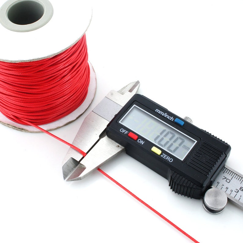 May include: A spool of red waxed cord with a digital caliper measuring the cord's thickness at 1.00 mm.