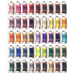 Puede incluir: Una colecci&oacute;n de carretes de hilo de varios colores, numerados del 201 al 606. Los carretes est&aacute;n dispuestos en filas y columnas sobre un fondo blanco.