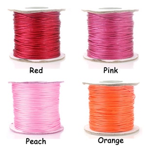 May include: Four spools of waxed cotton cord in red, pink, peach, and orange colors. The spools are on a white background.