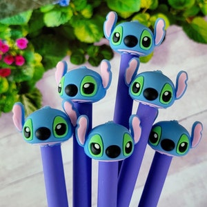 May include: Six purple pens with blue and green cartoon character heads. The characters have large eyes, a small nose, and a wide smile.