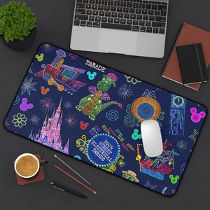 May include: A navy blue rectangular mousepad featuring colorful illustrations of a train, dragon, castle, fireworks, and Mickey Mouse icons. The mousepad has the words "PARADE" and "MAIN STREET ELECTRICAL PARADE".