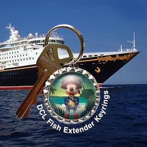 May include: A keychain featuring a pirate Mickey Mouse design. The keychain has a silver bottle cap design with the text "DCL Fish Extender Keyrings". A key is attached to the keyring, with a cruise ship and ocean in the background.