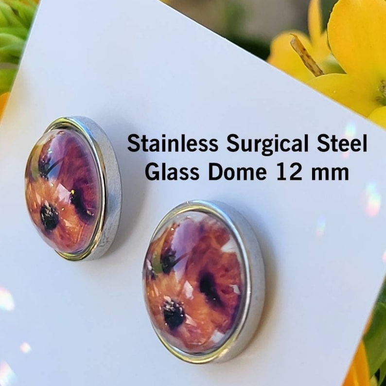 Puede incluir: Pendientes de bot&oacute;n de acero inoxidable con c&uacute;pula de cristal. Los pendientes presentan un dise&ntilde;o floral con tonos rojos, naranjas y negros. El texto de la imagen dice "Stainless Surgical Steel Glass Dome 12 mm."