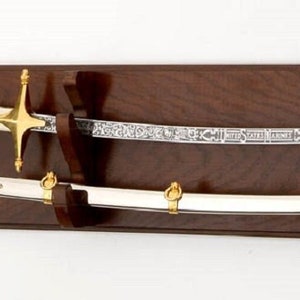 May include: A wooden wall mount with two swords displayed. The swords have gold accents and are mounted on a dark brown wooden background.