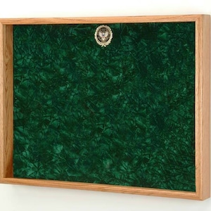 May include: A wooden frame with a green velvet interior. The frame has a small gold seal with an eagle design in the top center.