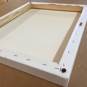 May include: A white canvas stretched over a wooden frame. The canvas is secured with staples along the edges of the frame.