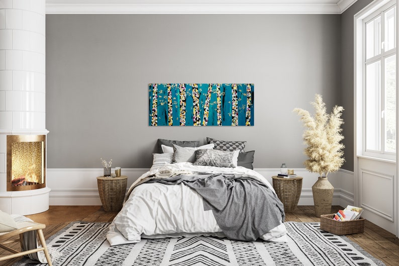 May include: A bedroom interior with a white bed, a gray throw blanket, and a large abstract painting of trees in shades of blue, yellow, and white hanging above the bed.