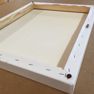 May include: White canvas stretched over a wooden frame with staples securing the canvas to the frame. The frame is made of wood and has a white finish.