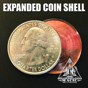May include: An expanded coin shell, featuring a United States quarter dollar and a copper-colored shell. The quarter displays the words "Liberty" and "Quarter Dollar". The text "Expanded Coin Shell" is at the top.