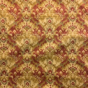 May include: Close-up of a fabric with a repeating damask pattern. The design features a mix of burgundy, olive green, and beige colors. The fabric has a textured appearance and a scalloped edge.