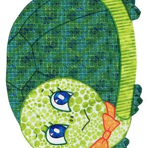 May include: A green turtle with a green and blue patterned shell, large blue eyes, and a bright orange bow tie. The turtle is lying on its back with its legs and head visible.