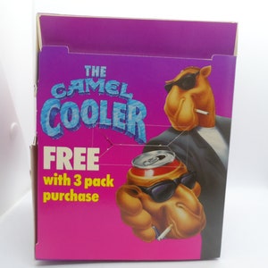 May include: A pink and purple cardboard box featuring a camel wearing sunglasses and a suit holding a can of soda. The box reads "The Camel Cooler" and "Free with 3 pack purchase".