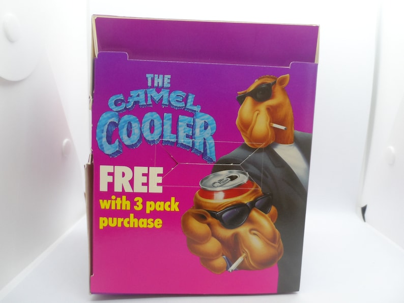 May include: A pink and purple cardboard box featuring a camel wearing sunglasses and a suit holding a can of soda. The box reads "The Camel Cooler" and "Free with 3 pack purchase".