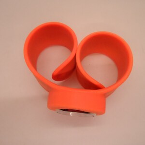 May include: Orange silicone watch band with a silver watch face.