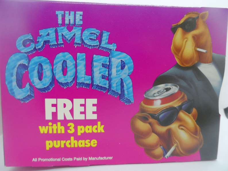 May include: A pink and blue advertisement for Camel Coolers. The ad features a cartoon camel wearing sunglasses and a suit, holding a can of soda. The text reads "The Camel Cooler FREE with 3 pack purchase. All Promotional Costs Paid by Manufacturer."