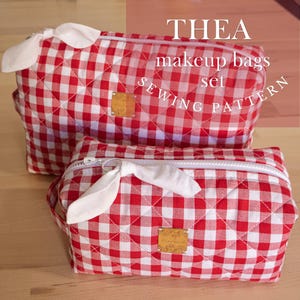 May include: Two red and white gingham makeup bags with white bows and gold-toned labels. The bags are quilted and have a zip closure. The text "THEA makeup bags set SEWING PATTERN" is visible.