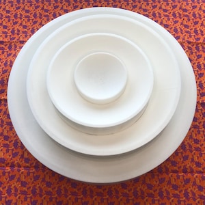 May include: A set of three white ceramic bowls, nested inside each other, with the smallest bowl in the center. The bowls are round and have a smooth, glossy finish.