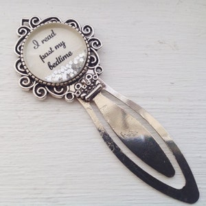 May include: Silver bookmark with a round glass charm that says "I read past my bedtime" and silver glitter inside. The bookmark has a decorative design and a silver metal bookmark tab.