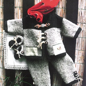 Puede incluir: Un conjunto de punto para bebé en gris y negro con una bufanda estampada en rojo y blanco. El conjunto incluye una chaqueta con un bolsillo y un pantalón con un detalle de botón.