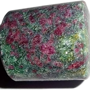 Peut inclure: Gros plan sur une pierre précieuse verte et rose avec une surface rugueuse et texturée. La pierre précieuse est de forme cylindrique et a un aspect marbré.