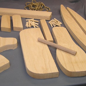 May include: A set of wooden pieces for building a rocking horse. The pieces are made of light-colored wood and include the head, body, legs, and rockers. There are also dowels and rope included in the set.