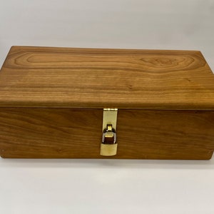 May include: A wooden box with a brass lock and latch. The box is made of light brown wood with a natural wood grain.