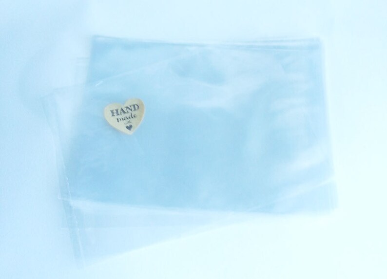 Puede incluir: Una bolsa de pl&aacute;stico transparente con una peque&ntilde;a etiqueta de madera en forma de coraz&oacute;n que dice "HAND made".