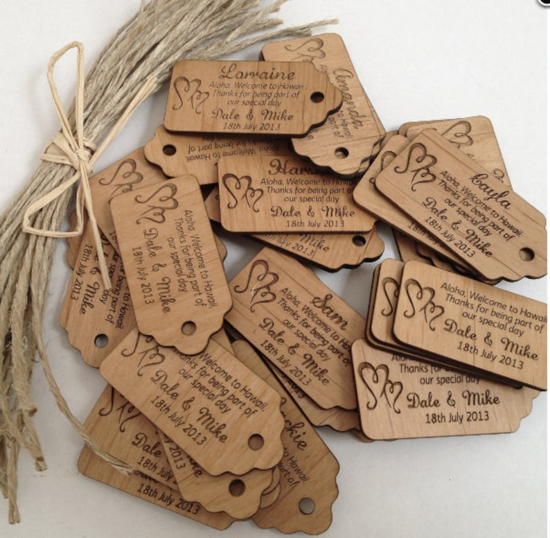 May include: A pile of wooden tags with a heart design and the text "Aloha, Welcome to Hawaii. Thanks for being part of our special day. Dale & Mike 18th July 2013" on each tag.