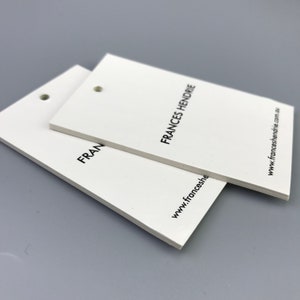 May include: Two white rectangular hang tags with rounded corners and a hole punched in the top left corner. The top tag has the text "FRANCES HENDRIE" printed in black. The bottom tag has the text "FRAN" printed in black. The text "www.franceshendrie.com.au" is printed in black on the right side of the top tag.